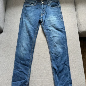 Blå skinny jeans från Jack & Jones - Snygga blå jeans från Jack & Jones med klassisk femficksdesign och kontrastsömmar. Modellen är skinny fit med smal passform och normal midja. Jeansen är tillverkade i bomull och har en stilren look som funkar till det mesta.