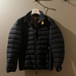 Parajumper jacka  - Säljer en svart dunjacka från Parajumpers i storlek XS. Jackan har klassisk quiltad design, hög krage med gul detalj och dragkedja framtill. Märkets ikoniska patch sitter på ärmen. Perfekt för kalla dagar och riktigt snygg streetstil.