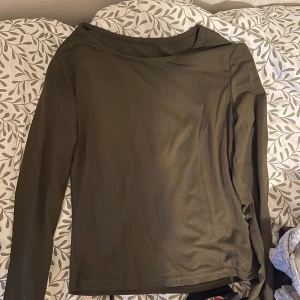 Olivgrön långärmad tröja - Enkel och stilren olivgrön långärmad tröja med rund halsringning. Tröjan har en rak passform och är tillverkad i ett mjukt, tunt material som känns skönt mot huden. Perfekt att matcha med jeans eller kjol för en avslappnad look.