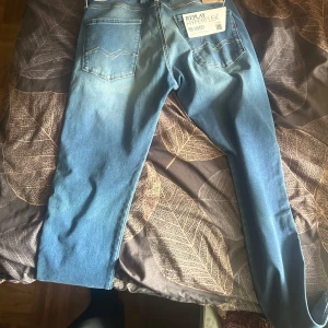 Replay Hyperflex blå jeans - Säljer ett par Replay Hyperflex jeans i klassisk blå tvätt. Jeansen har fem fickor, raka ben och snygga slitningar framtill. Materialet är stretchigt för extra komfort och passformen är normal. Perfekta för dig som vill ha ett par stilrena och bekväma jeans. den är helt ny inte ens använd