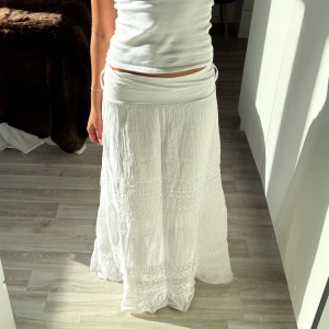 Vit långkjol med spetsdetaljer - Supersnygg vit långkjol med bred midja och flera lager. Köpt utomland, sitter som en s/xs