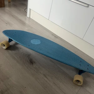 Blå skateboard  - Säljer en blå skateboard/longboard med plastdeck och vita hjul. Använd några gånger, funkar fortfarande som ny. 