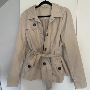 Beige trenchcoat med knappar - Snygg beige trenchcoat, perfekt till hösten!         Köpt secondhand o finns inga lappar i, gissar storlek är S-M💕💗