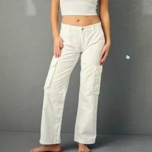 Vita cargopants med raka ben - Säljer ett par vita cargopants med raka ben och flera fickor på sidorna. Byxorna har hög midja och en loose passform som ger en chill och trendig vibe. Perfekta att styla med crop top eller hoodie för en avslappnad look.