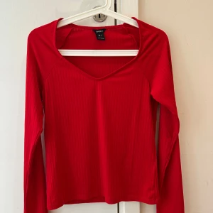  Ny Röd ribbad långärmad topp Lindex - Snygg röd långärmad topp från Lindex i storlek S. Toppen har ett ribbat tyg och en v-ringad hals som ger en fräsch vibe. Perfekt att matcha med jeans eller kjol för en cool look. Materialet är mjukt och stretchigt, vilket gör den skön att bära hela dagen.