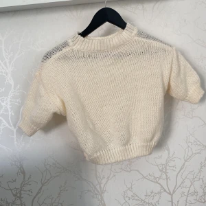 Stickad kortärmad tröja från SHEIN - Säljer en ljus stickad tröja från SHEIN i storlek M. Tröjan är kortärmad med ribbad hals och nederkant, och har en mjuk, luftig känsla tack vare materialet i 100% polyester. Perfekt för dig som gillar en clean och enkel look.