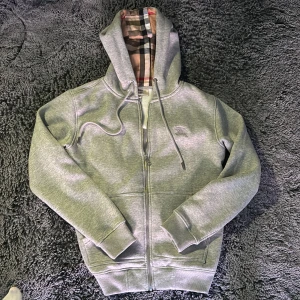 Grå hoodie från Burberry  - Säljer en grå hoodie från Burberry i storlek M. Tröjan har dragkedja, Storlek M, 10/10 skick
