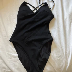Svart baddräkt med korsade band Lindex - Snygg svart baddräkt från Lindex i storlek S. Modellen har korsade smala axelband och en v-ringad front som ger en stilren look. Materialet är mjukt och stretchigt syntet, perfekt för strand eller pool. Enkel och klassisk design som passar dig som gillar minimalistiskt. Baddräkten är endast testad 1 gång och aldrig använd, även tvättad 