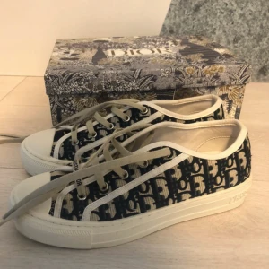 Christian Dior sneakers med monogram - Snygga sneakers från Christian Dior med klassiskt blått och beige monogrammönster. Skorna har snörning, rund tå och platt sula med stjärndetalj undertill. Skorna ör i 42 men sitter som 40,41 