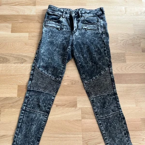Skinny jeans biker-modell strl 36 - Säljer ett par svarta skinny jeans från H&M DIVIDED, med coolt tvättad look och biker-inspirerade detaljer över knäna. Flera fickor med dragkedjor framtill och klassiska bakfickor. Lite långa för mig som är 159 men sitter annars snyggt. Passar S. 