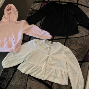 Ljusrosa hoodie med huva och 2 blusar storlek XS  - Säljer en ljusrosa hoodie med stor huva och magficka. Tröjan har ribbade muddar vid ärmslut och nederkant, perfekt för chill dagar. Mjuk och skön, passar dig som gillar enkel och clean stil. Och 2 blusar, vit och svart. Blusar är så gulliga och passar till vardagen. Alla är i storlek XS.😊
