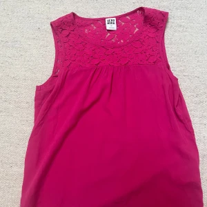 Rosa topp från Vero Moda - Snygg rosa topp från Vero Moda med ärmlös design och spetsdetaljer upptill. Blommönstrad spets vid axlar och hals ger en extra touch😍😍