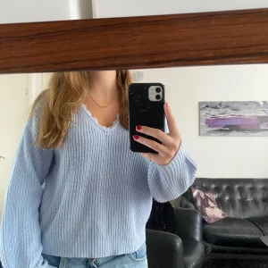 Ljusgrå stickad tröja med spets - Superfin ljusgrå stickad tröja med v-ringning och dekorativ spetskant runt halsen. Tröjan har ribbad struktur och långa ärmar med lite loose passform. Perfekt för dig som gillar mysiga och stilrena plagg med en söt detalj vid halsen.