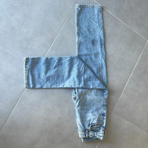 Ljusblå jeans från Grunt - Säljer ett par ljusblå jeans från Grunt med klassisk femficksdesign och raka ben. Jeansen har en snygg vintage-wash och är tillverkade i slitstarkt denimtyg. Passformen är normal och midjan är midwaist. Perfekta för en chill och avslappnad stil.