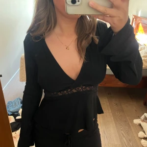 Svart omlottopp med spetsdetalj - Svart långärmad omlottopp med djup ringning och spetsdetalj. Den är från Gina och aldrig använd, med lappar kvar🫶🏽