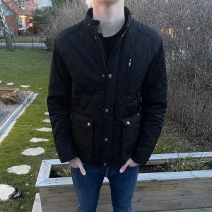 Svart quiltad jacka - Säljer en svart quiltad jacka med både dragkedja och knappar framtill. Jackan är från Selected Homme och är i storlek M! Modellen är 182 cm lång. Hör av dig vid minsta fundering! 