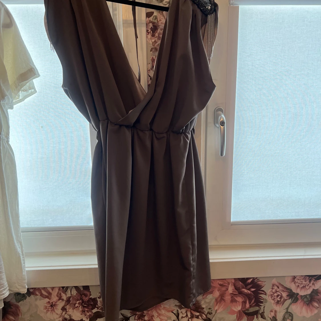 Mörkgrå klänning med djup v-ringning och pärldetaljer