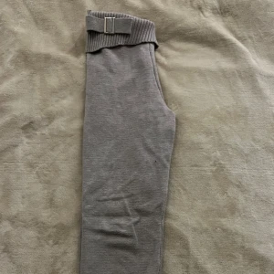 Ribbat Stickat Lounge grå  mjukts byxa. ÄKTA - Säljer ett par grå stickade byxor med bred ribbad midja och dekorativt bälte. Byxorna har raka ben och är supermjuka och bekväma, perfekta för en chill vardagslook.