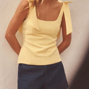 Gul linnetopp med rosetter på axlarna Zara - Supersöt gul linnetopp med breda axelband som knyts i stora rosetter. Toppen har fyrkantig ringning och figurnära passform, perfekt för varma dagar. Helt ny endast testad💖