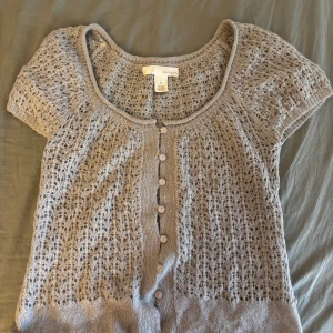 Grå stickad kofta från Kaisly - Kortärmad grå stickad kofta. Tunt och extremt mjukt material och fin virkning. Koftan är i storlek M men passar även S