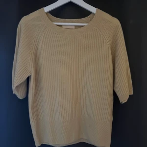 Beige ribbstickad kashmirtröja - Säljer en beige ribbstickad tröja i mjuk kashmir med rund halsringning och trekvartsärm. Perfekt för dig som gillar en enkel och stilren look. Tröjan är i storlek M och har en klassisk passform.