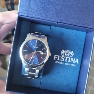 Herrklocka från Festina - Köpt för ungefär 1000kr. Säljer för 500kr. Knappt använd.                                                 Stilren herrklocka från Festina med blå urtavla, silverfärgat armband i metall, och datumvisning. 