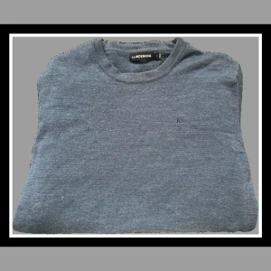 Blå stickad tröja från J.Lindeberg - Säljer en stilren blå stickad tröja från J.Lindeberg. Tröjan har rund halsringning och en diskret broderad logga på bröstet. Perfekt för lager-på-lager och passar till många olika outfits.