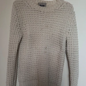 Vit stickad tröja från Acne Studios - Säljer en vit stickad tröja från Acne Studios i storlek XS. Tröjan har ett grovt, luftigt stickat mönster och rund halsringning. 