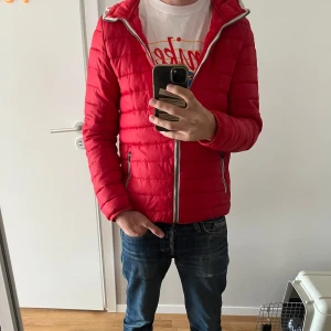 Röd jacka.  - En röd tunn jacka. Står XS men modellen på bilden är 182 och väger 62kg men känns lite liten. så sitter mer som S-M. Perfekt nu till våren.