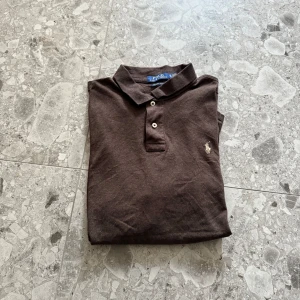 Brun pikétröja från Polo Ralph Lauren - Brun pikétröja från Ralph Lauren i väldigt fint skick. Ett perfekt alternativ för sommaren och är väldigast trendig just nu😊
