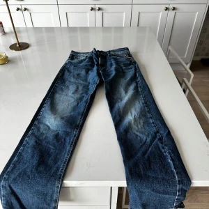 Blå Replay jeansbyxor - Säljer ett par klassiska blå jeans från Replay med raka ben och normal passform. Byxorna har fem fickor, dragkedja och knapp i midjan samt Replay-logga på bakfickan. Perfekta för dig som gillar tidlös denimstil. Storlek 158