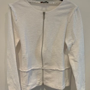 Vit jacka med dragkedja från Street One - Säljer en stilren vit jacka från Street One med lång ärm och dragkedja framtill. Jackan har en lätt strukturerad yta och rund halsringning. Perfekt för en clean och enkel look.