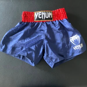 Thaiboxnings Shorts Venum - Helt oanvända Muay Thai shorts från Venum. Perfekta till när du tränar kampsport och behöver ett par shorts som låter dig spark fritt. Storleken är: L me sitter perfekt på mig som brukar ha S. Beror på att dem har annorlunda storlekar i Thailand. / Isac