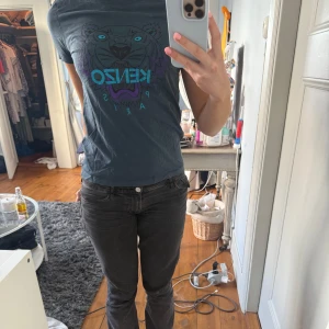 Mörkgrå/blå Kenzo t-shirt med tigertryck - Säljer en mörkgrå/blå t-shirt från Kenzo med ikoniskt tigertryck och turkos Kenzo-logga på bröstet. T-shirten har rund halsringning och korta ärmar. Perfekt för dig som gillar sommarkläder och vill sticka ut med en snygg design.