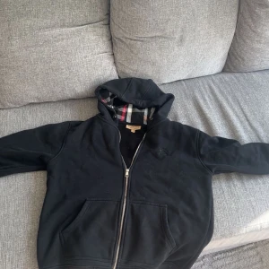 Svart hoodie från Burberry - Hej säljer nu denna fina Burberry hoddien! Storlek L men sitter bäst som M! Snöret är borttappat tyvärr. Jätte fint skick. Hör av er vid frågor eller bilder. Priset inte hugget i sten