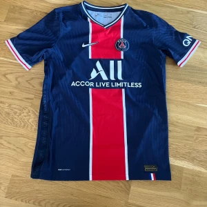 PSG hemmatröja Nike storlek 147 158 50kr plus frakt  - Säljer en Paris Saint-Germain fotbollströja från Nike med klassisk röd och vit rand på mörkblå bas. Tröjan har korta ärmar, broderad Nike-logga och PSG-emblem på bröstet. Materialet är lätt och ventilerande.