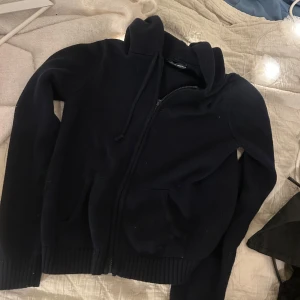 Svart stickad hoodie med dragkedja 100kr, sparsamt använd  - Säljer en mörkblå stickad kofta med dragkedja och huva. Brandy Malville, 100kr