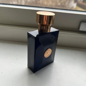 Versace Pour Homme Dylan Blue  - Versace Pour Homme Dylan Blue är en maskulin parfym i en elegant mörkblå glasflaska med gulddetaljer och rund guldlogotyp. Flaskan har en lyxig, geometrisk form och kommer i en matchande blå och guld kartong. Volym: 50 ml.