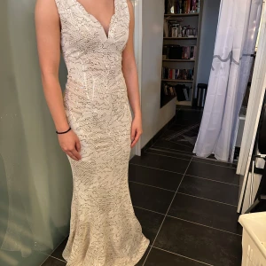 Vit långklänning med paljetter och v-ringning - Säljer en elegant vit långklänning från Oasis med v-ringning och glittriga paljettdetaljer. Klänningen har figurnära passform och är ärmlös, perfekt för bal eller festliga tillfällen. Storlek 38 men passar mer som 36/s