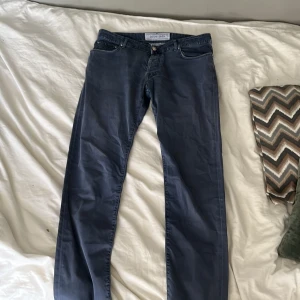 Mörkblå jeansbyxor från Jacob Cohen - Säljer ett par mörkblå jeansbyxor från Jacob Cohen. Klassisk femficksmodell med raka ben och normal passform. Byxorna har dragkedja och knapp i gylfen samt diskret logga på bakfickan. Loggan därbak på byxan är lite sliten vill tilläggas.