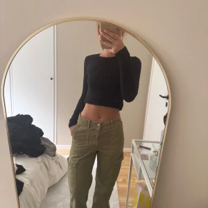 Olivgröna cargobyxor med raka ben - Säljer ett par olivgröna cargobyxor med raka ben och fickor på sidorna. Byxorna har hög midja och stängs med dragkedja och knapp framtill. Perfekta för en avslappnad och trendig stil.