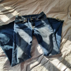 Blå bootcut jeans från Monki - Säljer ett par blå bootcut jeans från Monki med snygg slitning och broderade gula rosetter på bakfickorna. Jeansen har klassisk femficksdesign, knappgylf och är tillverkade i jeansmaterial. Perfekta för dig som gillar en retro vibe och unika detaljer. SÄLJER FLER JEANS!!!!❤️❤️❤️