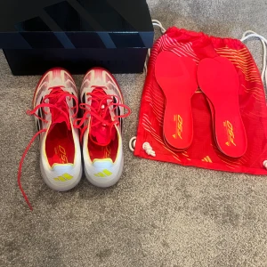 Adidas F50 Elite AG fotbollsskor - Säljer ett par Adidas F50 Elite AG fotbollsskor i vitt, rött och gult med svarta detaljer. Skorna har snörning, rund tå och platt sula med fasta dobbar. Kommer med extra innersulor och röd skopåse. 43 och 1/3. Endast använda en uppvärmning