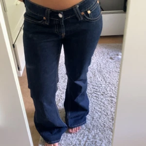 lågmidjade levis jeans - Mörkblå Levis 501 jeans med klassisk femficksdesign och raka ben. Byxorna har synliga kontrastsömmar och Levis ikoniska läderpatch baktill i midjan. Passar perfekt till en avslappnad och tidlös stil. Strl w31 l32 midjemått ca 44