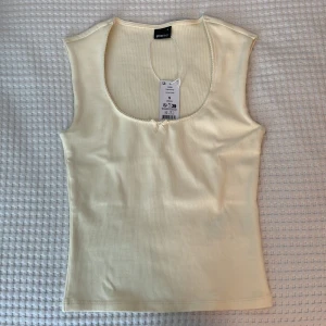 Ljusgul ribbad linnetopp Gina Tricot - Helt ny ljusgul topp med prislapp kvar. Toppen är ribbad med rundad urringning + rosett. Färgen är mer som på de sista bilderna. Aldrig använd💛🎀Skriv för fler frågor!🤗