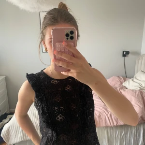 Svart topp - Säljer en svart ärmlös topp med vacker spetsdetalj. Klänningen har en figurnära passform och är perfekt för dig som vill ha en elegant look. Passar lika bra till sneakers som till klackar.