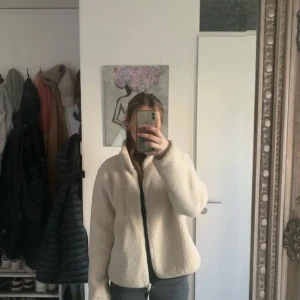 Beige teddyjacka från Gina Tricot - Mysig beige teddyjacka från Gina Tricot med dragkedja framtill. Jackan har lång ärm och en rak, något oversized passform. Perfekt för kyligare dagar och enkel att matcha med olika outfits.