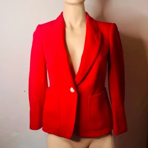 Röd kavaj / blazer från Zara Woman – figursydd powerlook- XS - Skarpt röd kavaj från Zara Woman i figursydd modell med markerade axlar och djup krage. Sitter snyggt och ger en kraftfull silhuett – perfekt till både vardag och fest. Helfodrad med randigt innerfoder och två fickor framtill. Storlek: XS. Skick: Mycket fint begagnat skick. Ingen prutning, men jag erbjuder bundlerabatt vid köp av flera plagg. Kolla gärna mina andra annonser också!  ⸻ 