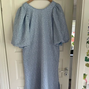 Ljusblå blommig långklänning Noella - Superfin ljusblå långklänning från Noella med puffiga korta ärmar och sött blommönster. Perfekt för sommarens alla tillfällen! Storlek XXL, men skulle jämföra den med en XL. Midjemått: 85, Byst: 102. Nypris 999kr