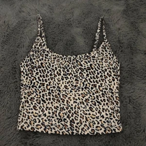 Leopardmönstrad croppad linnetopp - Säljer en croppad linnetopp med leopardmönster. Toppen har smala axelband och är perfekt för dig som vill sticka ut med ett djurmönster. Materialet känns mjukt och stretchigt.
